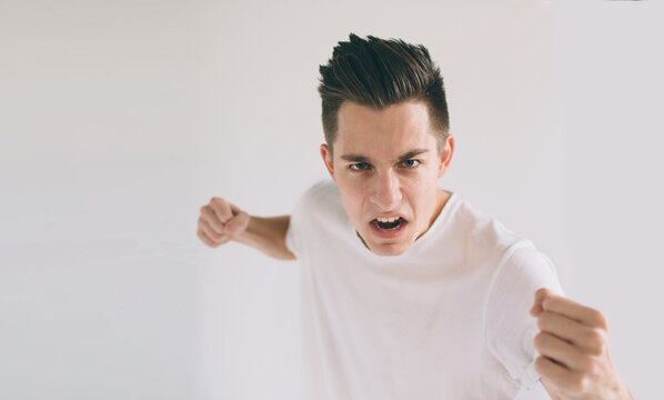 portrait of a angry young man. He is clenches fists and shouts.. The wicked guy beats .