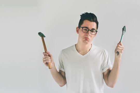 Funny portrait upset craftsmen. Nerd is wearing glasses.. Does not know how to use tools for repair
