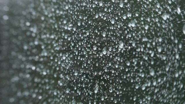 Wet window with rain bead patterns and downward camera tilt