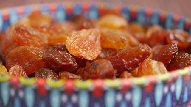 A close up slow motion video of dried raisins in bowl, vibrant colors and healthy snack footage.