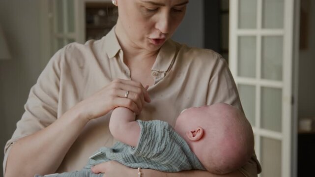 Caucasian mother soothing and bonding with infant baby in arms at home. Visual suited for maternal healthcare campaigns, parenting content, baby care marketing and family wellness promotions