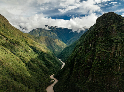 Aerial view of the Urubamba River winding through the lush green jungle landscape of the Andes mountains near Aguas Calientes, Cusco, Peru.