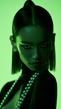 neon green portrait of an elegant east asian woman with pearls, dramatic beauty portrait with bold eyeliner and neon lighting, futuristic portrait of an woman with slicked back hair
