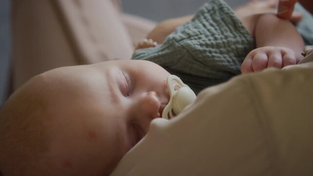 Caucasian mother gently stroking sleeping baby with pacifier over shoulder. Clip suitable for newborn care advertising, maternity promotions, and parenting campaigns