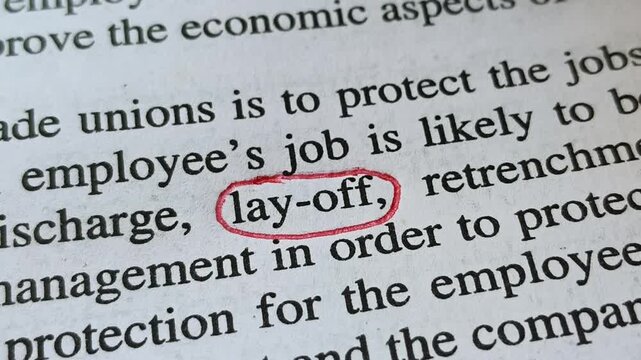 Employee worker hand with red ink pen mark circle around to emphasize or highlight Lay-off word printed on news paper or document page. IT industry layoffs crisis or problems symbolic concept.
