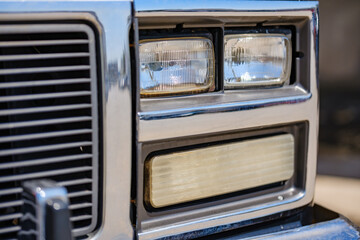 Vintage squarebody American pickup truck chrome headlight bezel featuring dual rectangular glass lamps and turn signal indicator light © Bugra Kaan Ersoy