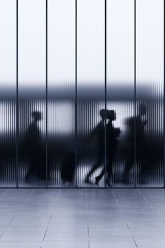 3D office corridor with blurred business silhouettes behind dark ribbed glass partition