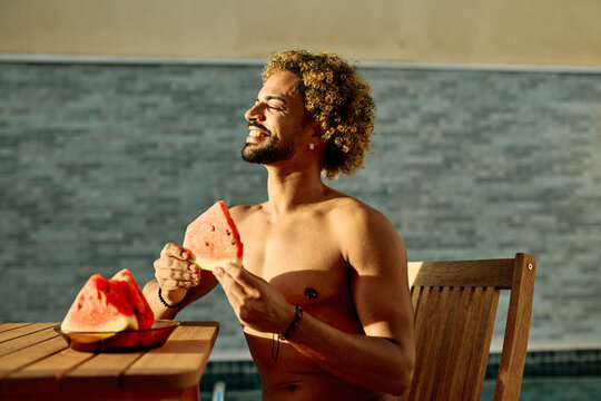Young man enjoy watermelon fruit and beer bottle drink or alcohol and juice while sitting in water at a pool area in a warm location during summer
