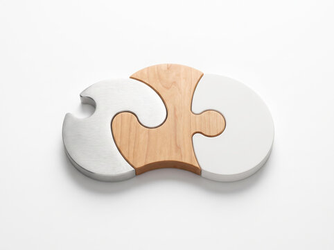 Top view of three curved interlocking jigsaw puzzle elements made of polished natural wood and smooth white material connected together.
