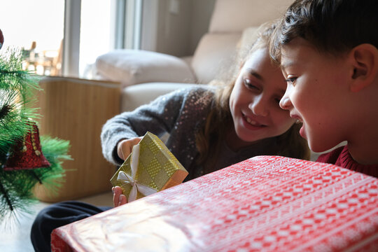 Children excitedly opening christmas gifts with a tree