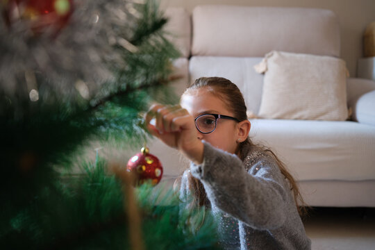 Little girl decorating christmas tree at home
