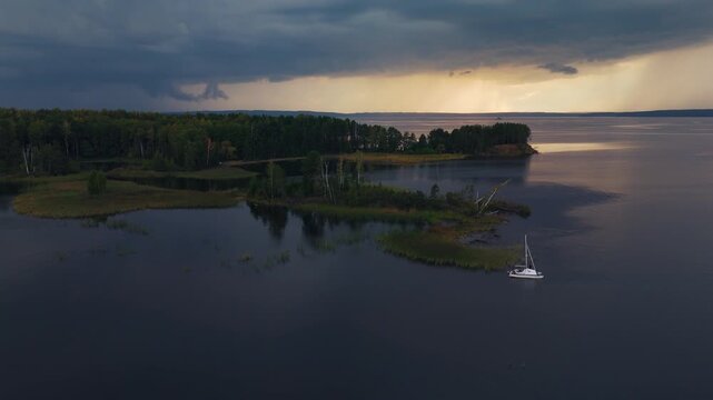 Sailing vessel hides in the calm lagoon on the lake before the incoming storm. Votkinsk reservoir of the Kama river in Russia