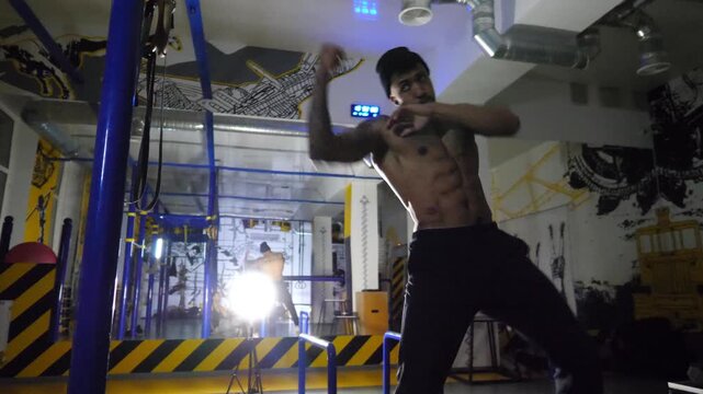 Muscular african boxer demonstrating punches at sport club. Young afro american sportsman practicing shadow boxing at modern gym. Strong black kickboxer training indoor. Healthy lifestyle concept