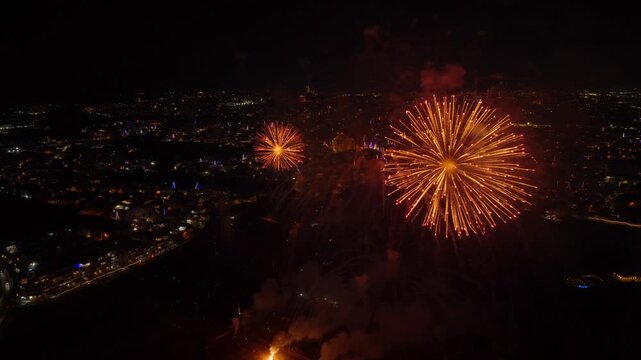 Aerial drone shot of vibrant fireworks exploding in the sky during a festive celebration, with a church in the background