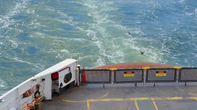 Ferry departs Bowen Island, leaving swirling wake in blue coastal waters