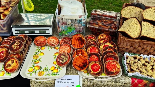 Rustic breads, savory pastries and croutons are arranged in baskets and trays at an outdoor food stall
