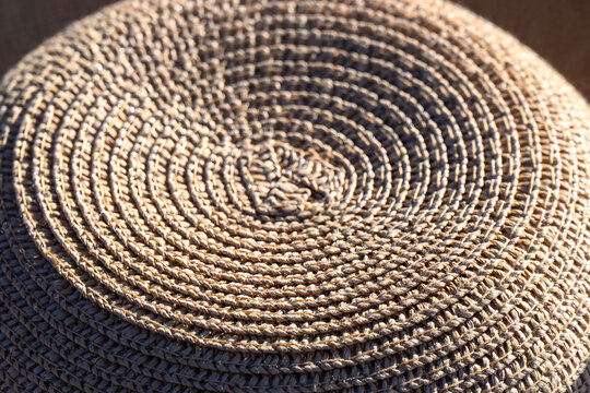 Macro texture of a woven straw hat crown with circular spiral pattern.