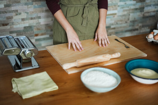 Woman preparing dough for tagliatelle at home - Handmade food and italian culture concept - Main focus on right hand - UGC content