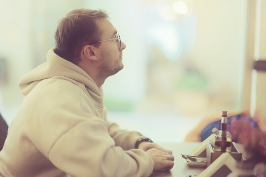 Casual Cafe Atmosphere: Man in Hoodie Relaxing with Soft Focus Background