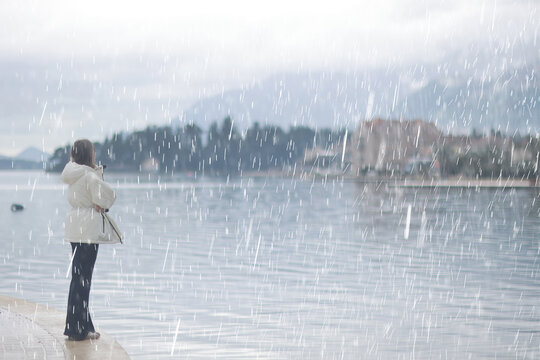 Solitary Reflection: Woman in White Jacket Observing Rainfall by Serene Lake