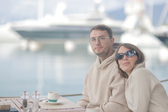 Couple Relaxing at Waterfront Caf&eacute; with Marina and Yachts in Background
