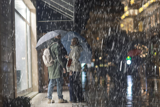 Couple Shelters Under Umbrella in Nighttime Urban Rain Scene with City Lights