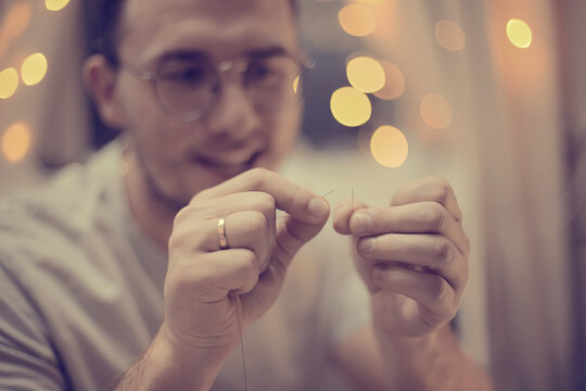 Man Threading Needle with Bokeh Lights in Background