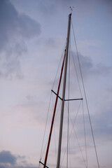 Detail of a sailboat mast and spreader with wire rigging pointing towards a cloudy evening sky at nautical twilight © Bugra Kaan Ersoy