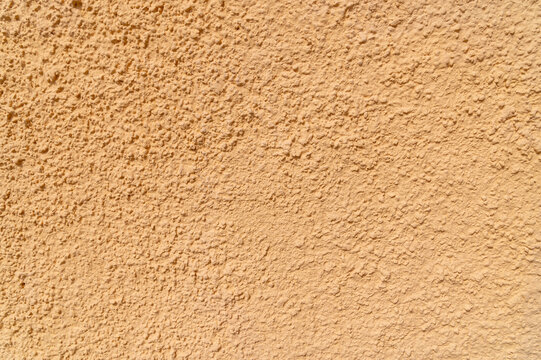 Textured peach stucco wall surface with rough plaster finish