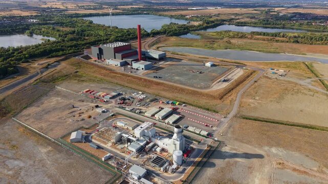 Aerial view of Rookery South ERF and Millbrook Power plant with its tall red chimney, industrial structures, and surrounding lakes in Stewartby, England, United Kingdom.