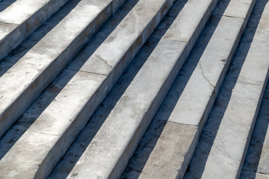 Marble steps descending with diagonal shadows on outdoor staircase