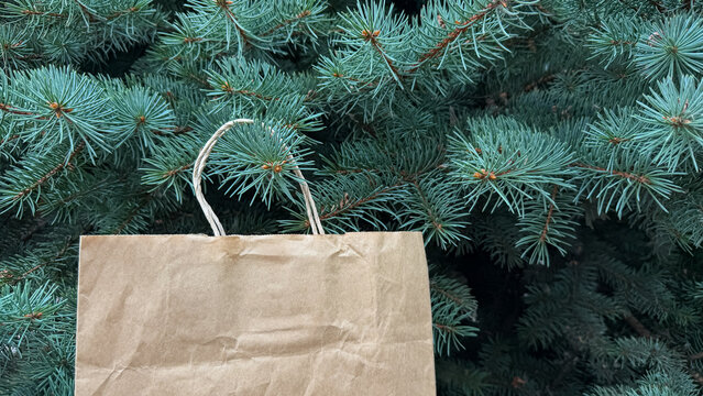 Craft paper bag nestled in green pine tree branches, sustainable gift delivery, christmas celebration.