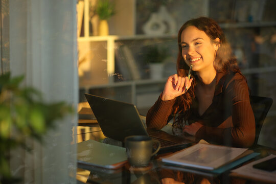 Happy telecommuter thinking looking through a window working