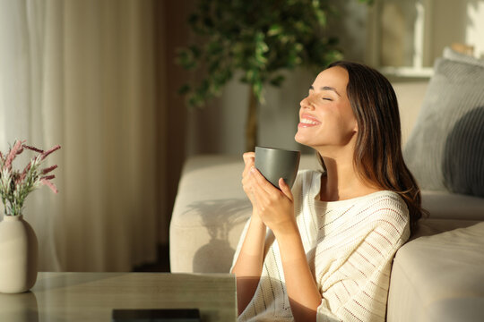 Happy woman smelling coffee and relaxing at home