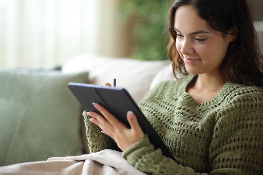 Satisfied young woman handwriting on tablet using digital pen
