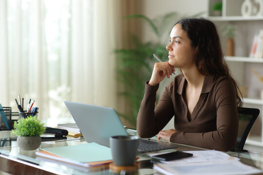 Proud and pensive teleworker looking away working at home