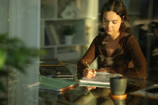 Young telecommuter filling out paper form working at home