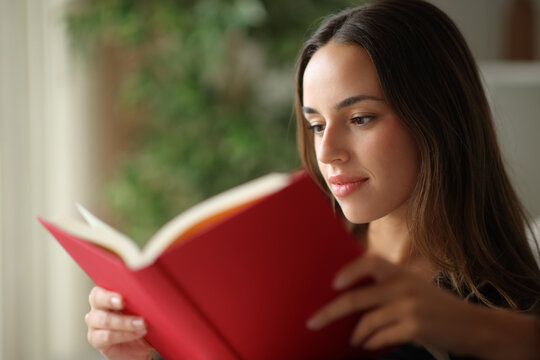 Woman reading red paper book in a living room