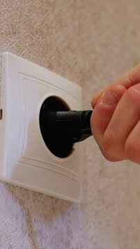Close up view of hands plugging and unplugging devices. hand inserts or removes plugs from electrical sockets demonstrating proper connection plug socket