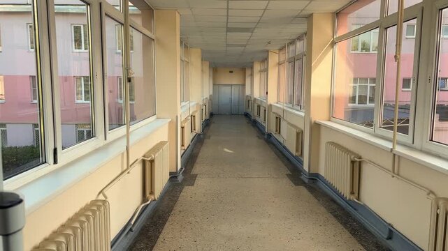 Sunlit empty hospital corridor with large windows and radiators in a medical facility