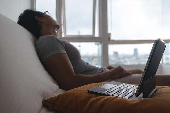 Young man relaxing on a comfortable sofa with a tablet and keyboard, enjoying a break.