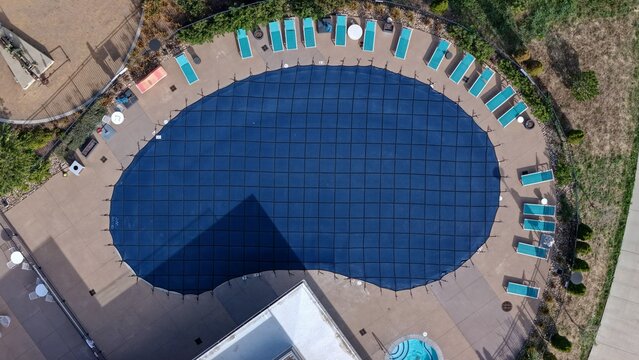 Aerial view of a swimming pool covered with a blue safety net, surrounded by lounge chairs on a concrete deck in Boulder, Colorado, United States.