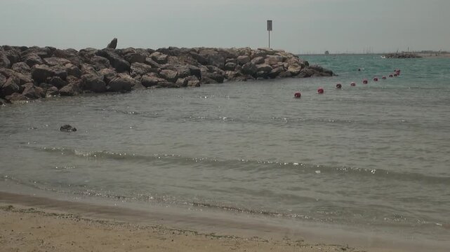 Beach breakwater rock buoy coast Cunit Mediterranean sky sunlight pan