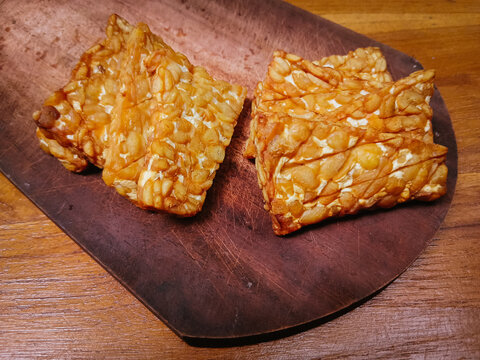 Sliced fried tempeh or tempe, traditional Indonesian soybean food on wooden board