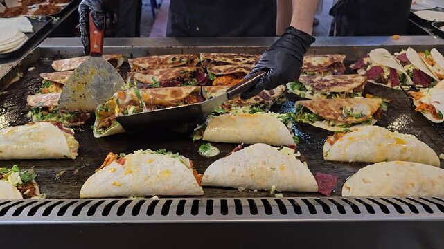 Mexican Tacos and Quesadillas Cooking on Large Flat Top Griddle Grill