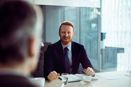 Smiling businessman talking with colleague in modern office