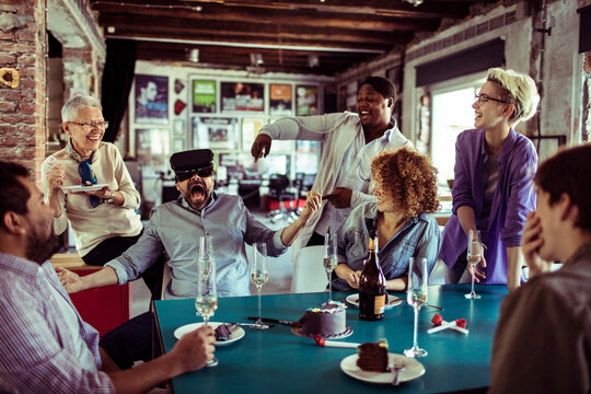 Friends laughing as man tries vr headset at party