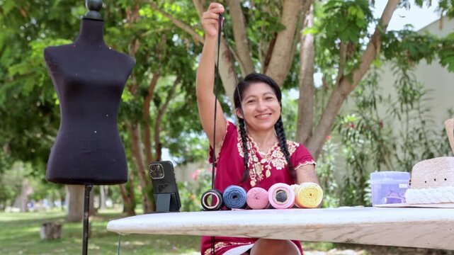 Indigenous artisan woman weaving macrame at an outdoor park market