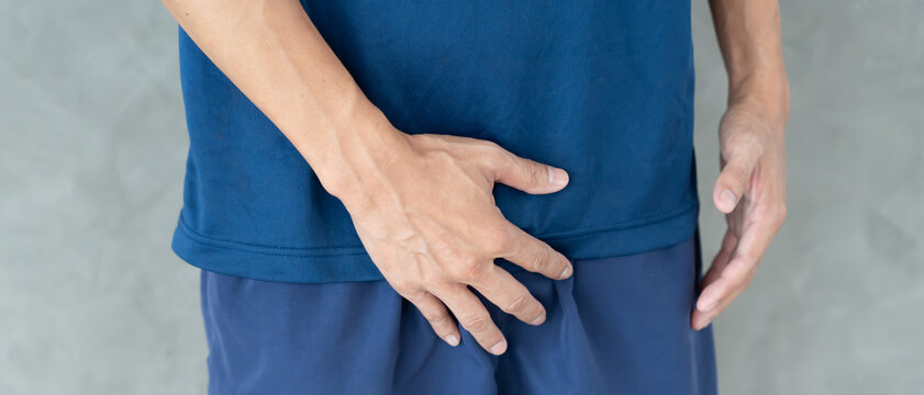 Man hold hand in front of private parts feeling discomfort from disease and inflammation. Venereal, testicular cancer. bladder problems, erectile dysfunction, premature ejaculation, prostate cancer