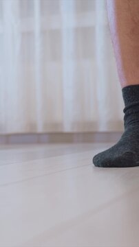 Shows lower leg and socked feet as someone mops with only part of their foot visible. mop moves across light colored floor while dark socks remain stationary